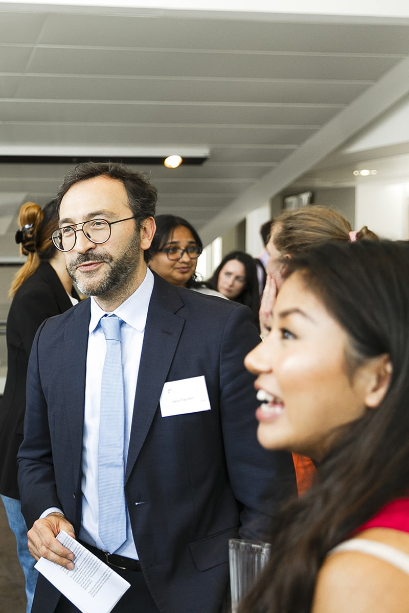 Close up of two people at a business networking event with a few people in the background