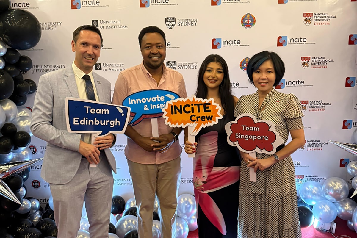 Four people at an INCiTE event holding signs for Team Edinburgh, Team Singapore, and Incite Crew.