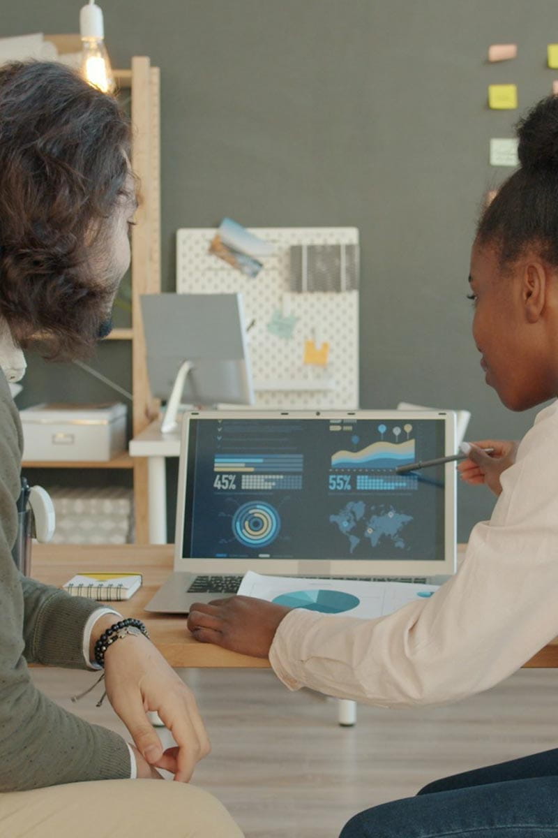Two people looking at a screen displaying data