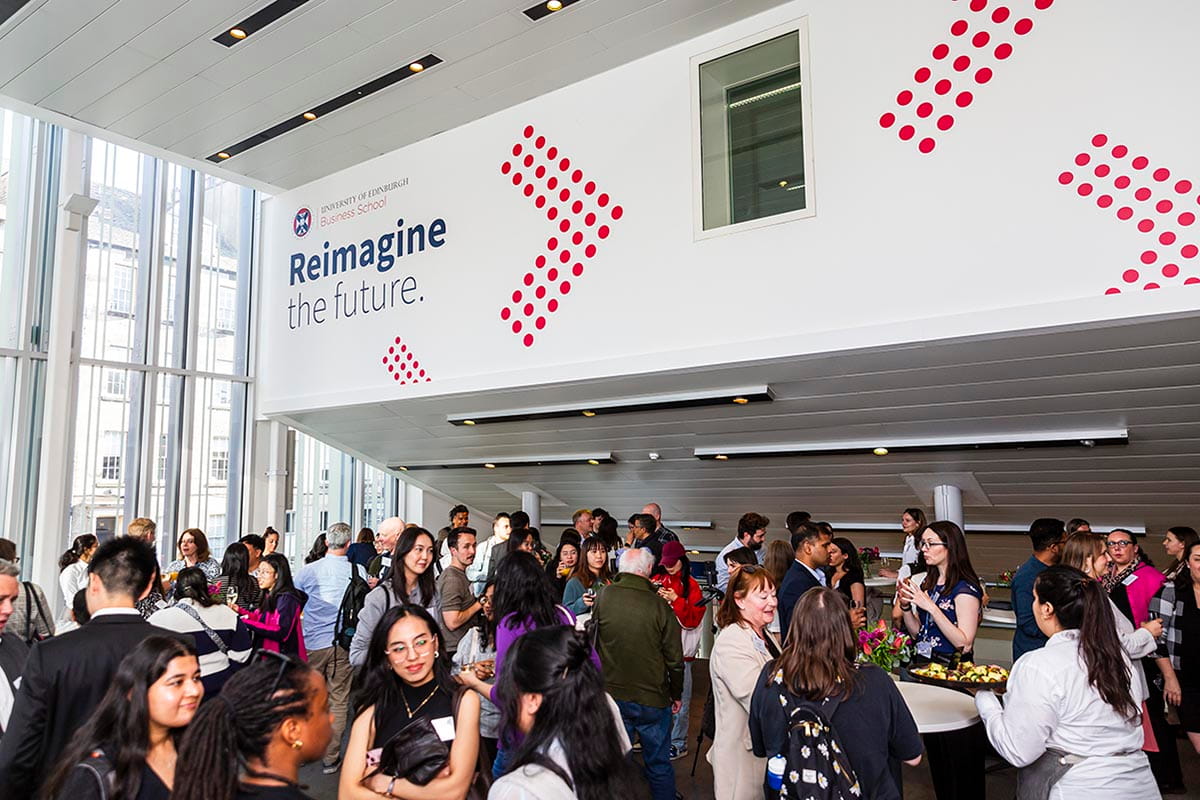 Large gathering of attendees socialising at the University of Edinburgh Business school Concourse