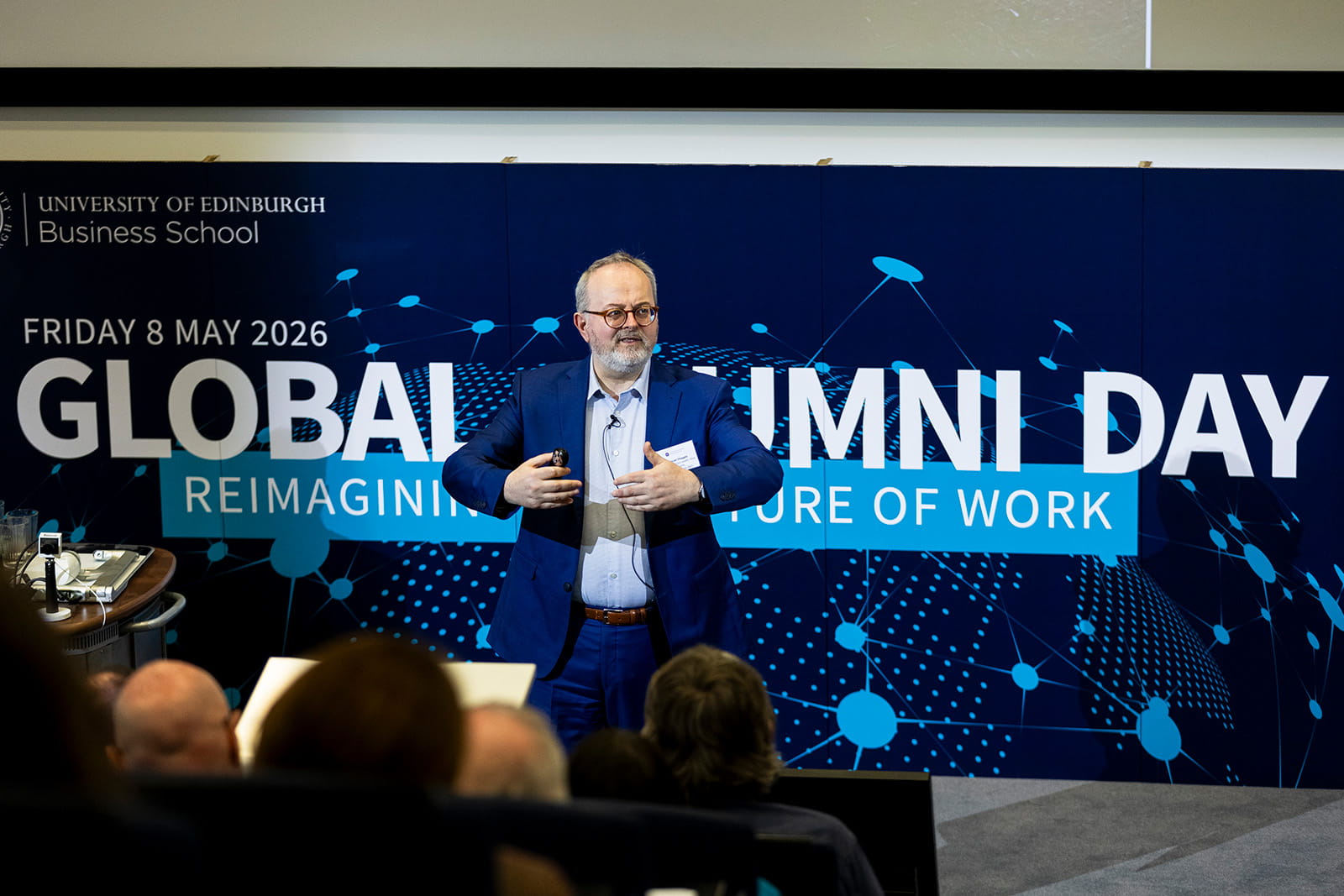 A speaker in a blue suit addresses an audience at the University of Edinburgh Business School’s Global Alumni Day.