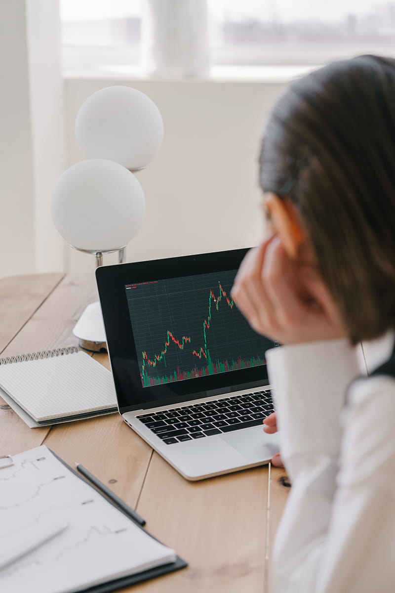 Person sitting in front of a laptop showing finance graphs