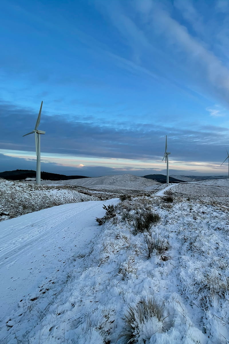 Two wind turbines on a hill in winter