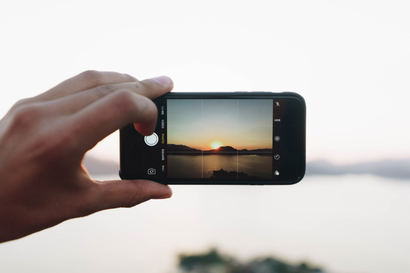 Person taking photo of a sunset on camera phone