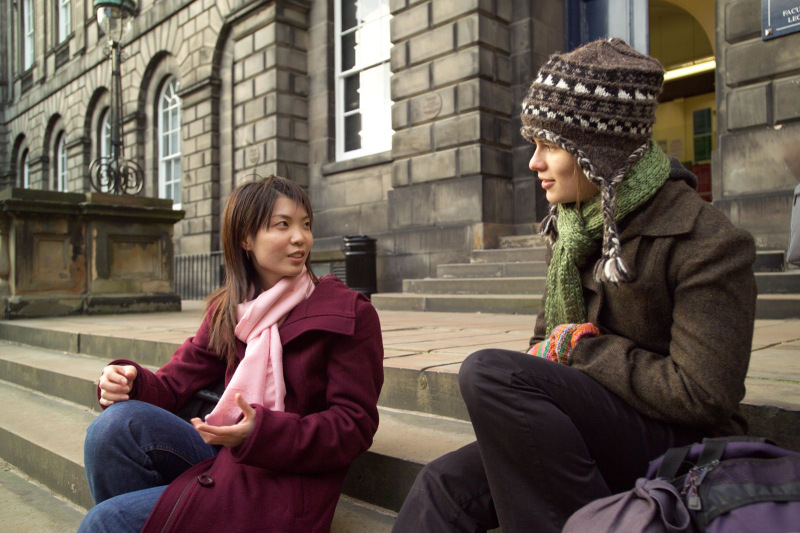 Two students sitting on the steps at Old College