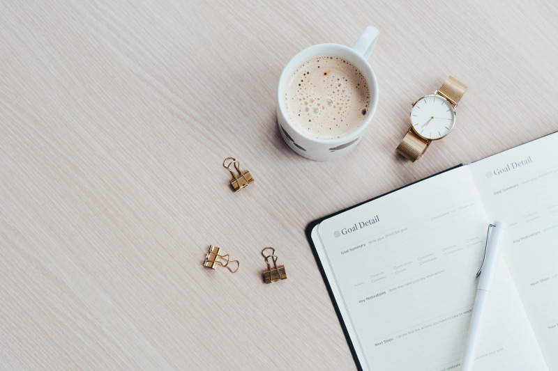 Goal setting notebook with coffee, watch, bulldog clips
