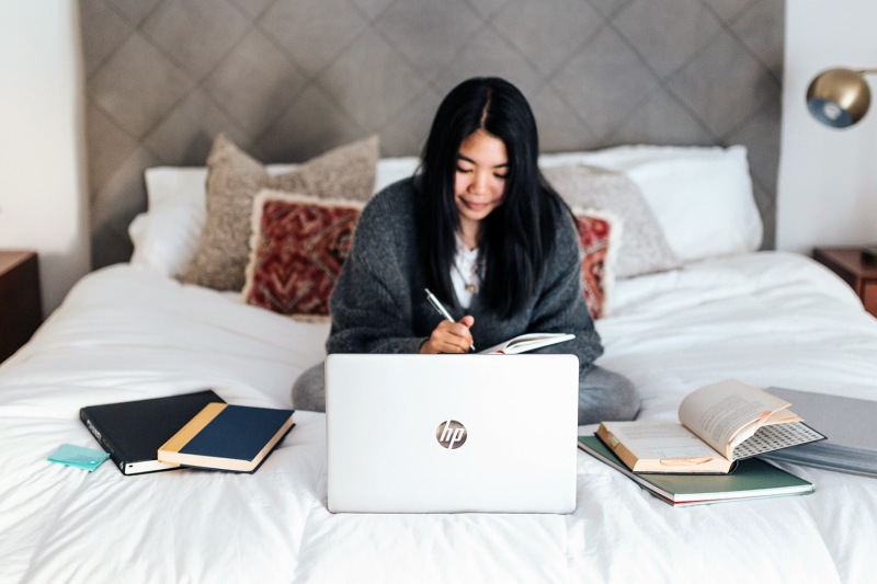 Girl taking notes while also using her laptop