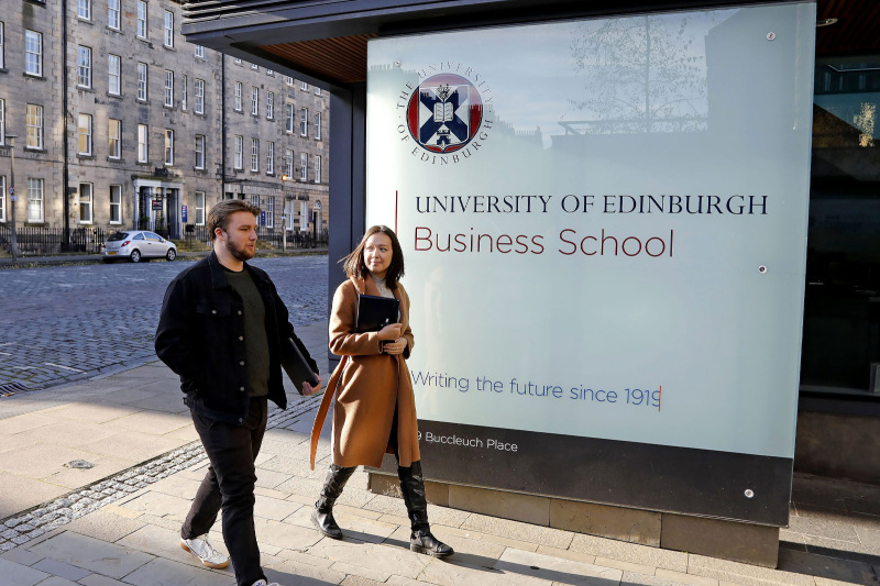 Students walking in front of the Business School Sign