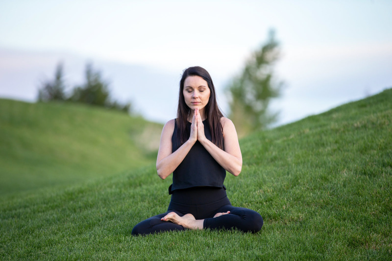 A woman mediating in a green field 