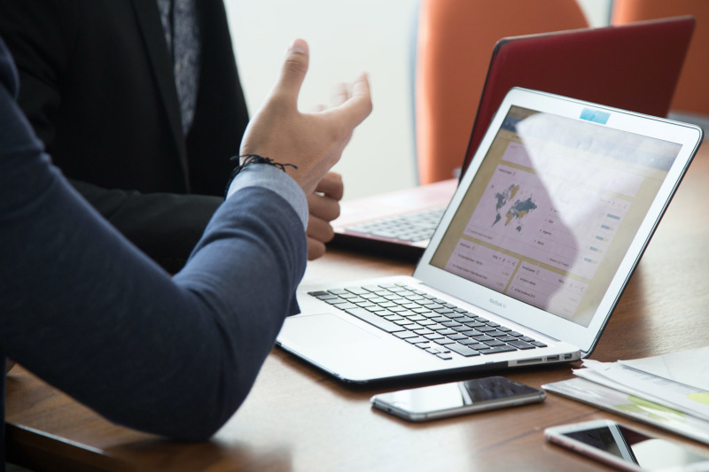 A women with a computer in front of her and speaking with a man beside her