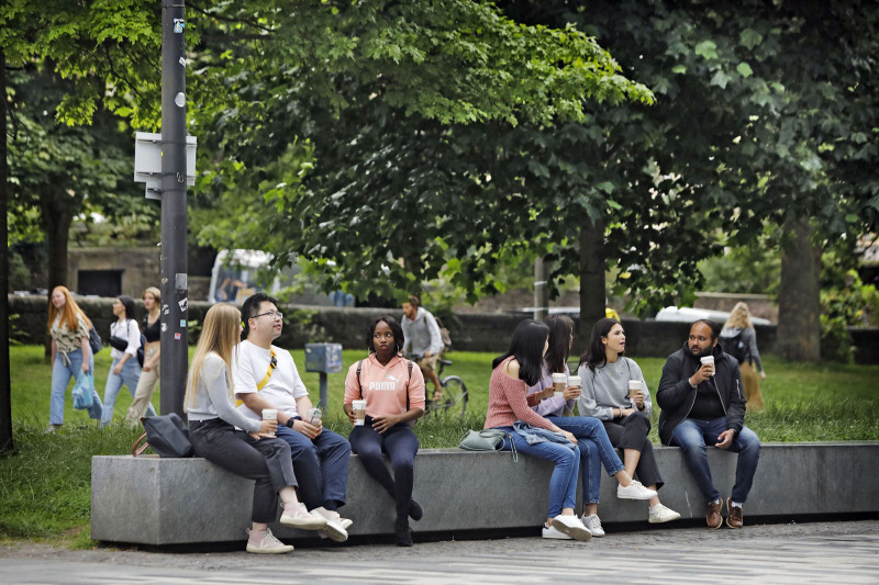 Various Business School students sitting outside campus on a bench