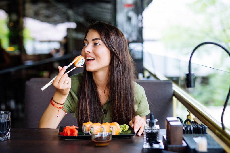 Girl at a restaurant eating sushi with chopsticks