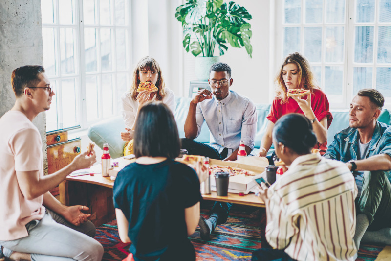 Students eating pizza together in a common living area