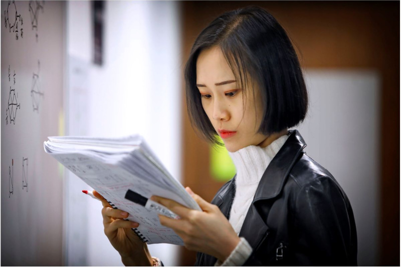 Student with research papers writing notes on a whiteboard