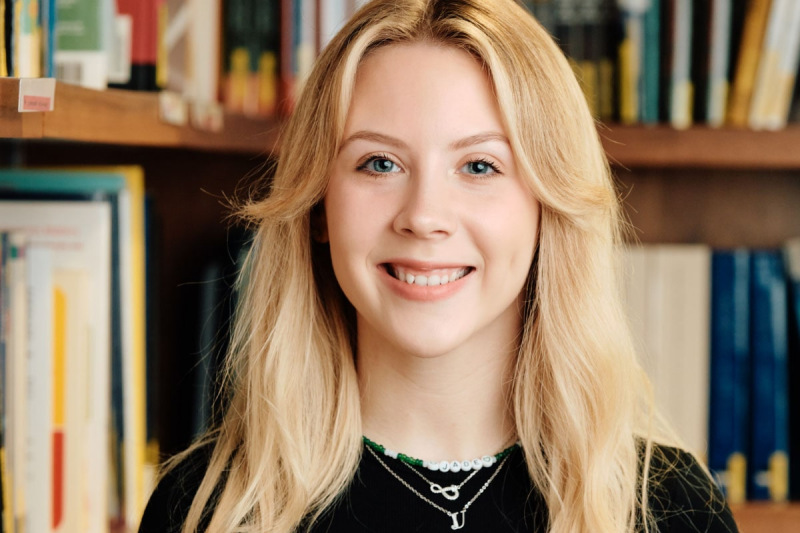 Staff photo of Jade Urwin in front of bookshelves 