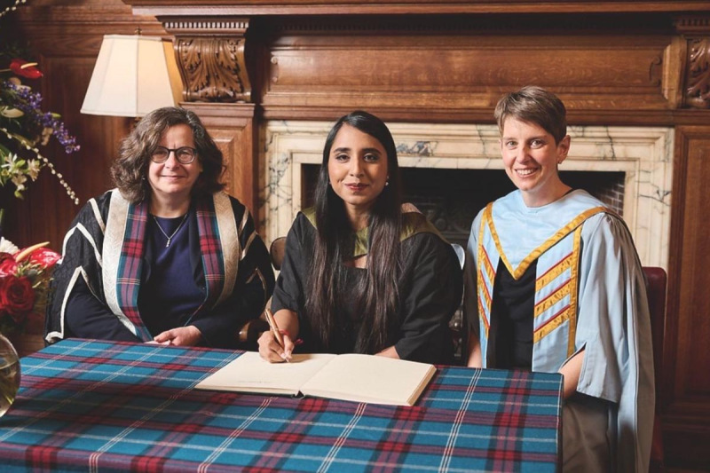 Three people sitting behind table at awards ceremony
