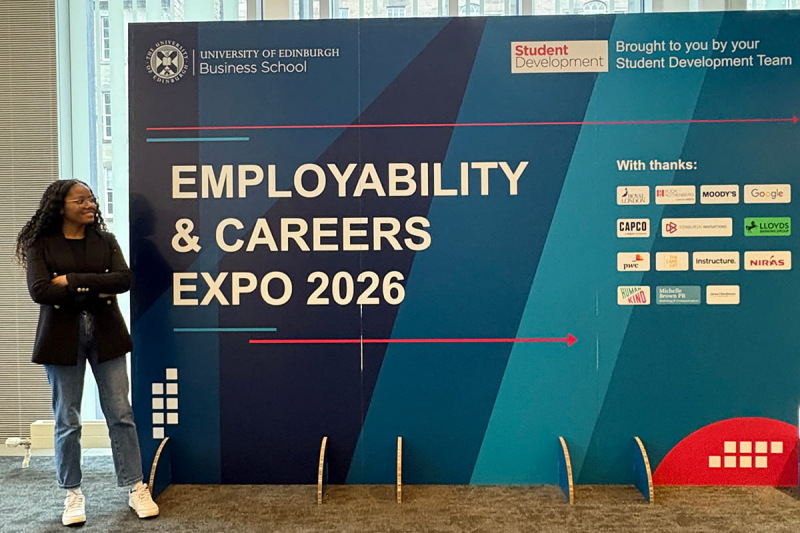 Person stands beside large sign for University of Edinburgh Business School's Employability & Careers Expo