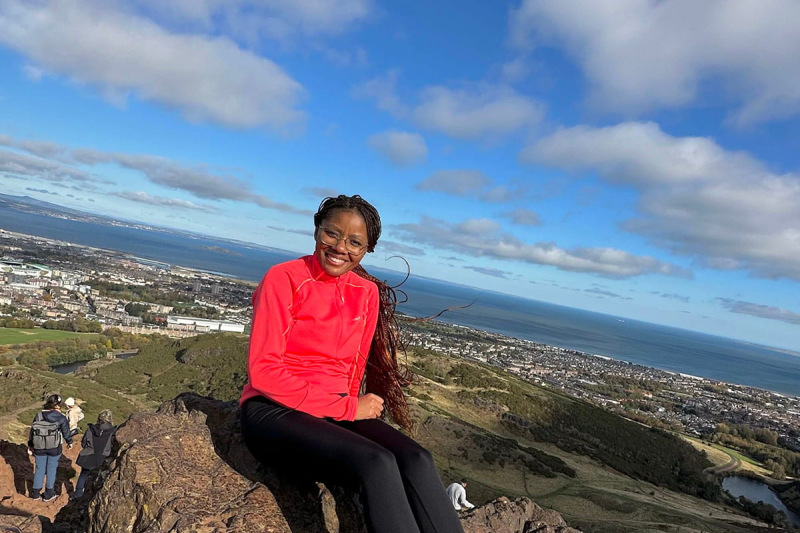 MSc student Keaobaka sitting at the top of Arthur's Seat in Edinburgh