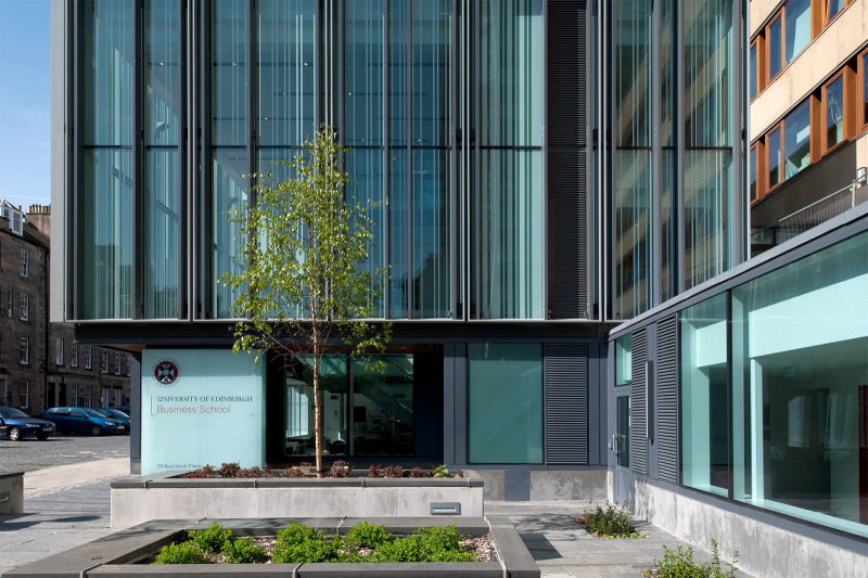 The south-facing entrance of the University of Edinburgh Business School, featuring a glass facade and tree situated in the courtyard.
