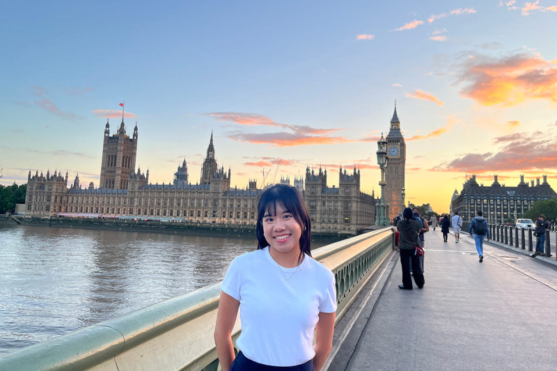 MSc student on bridge in London with sunset in background