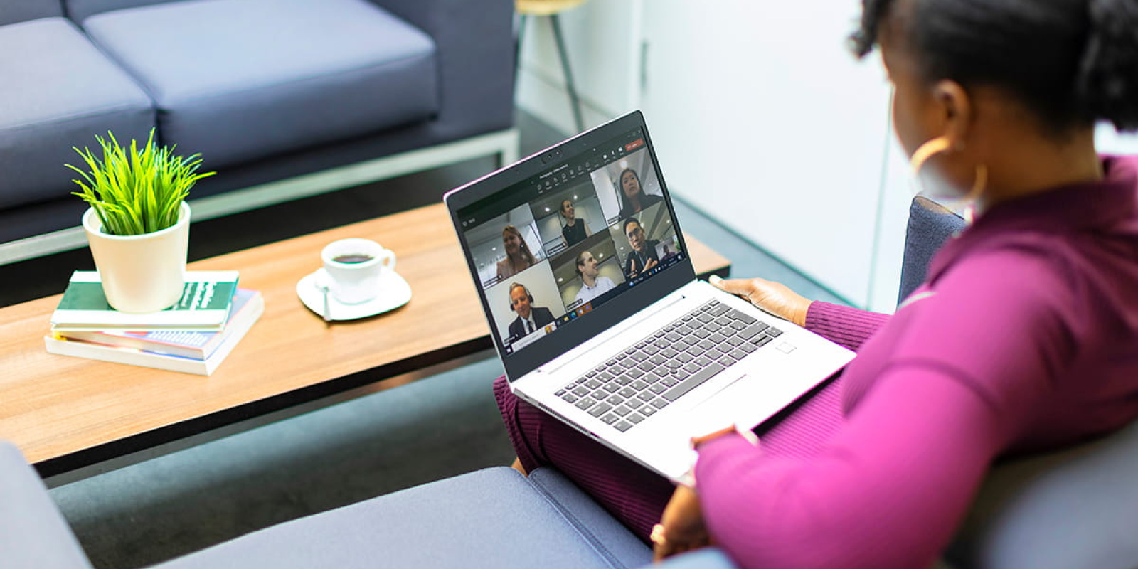 Student sitting on a sofa attending an online meeting on their laptop