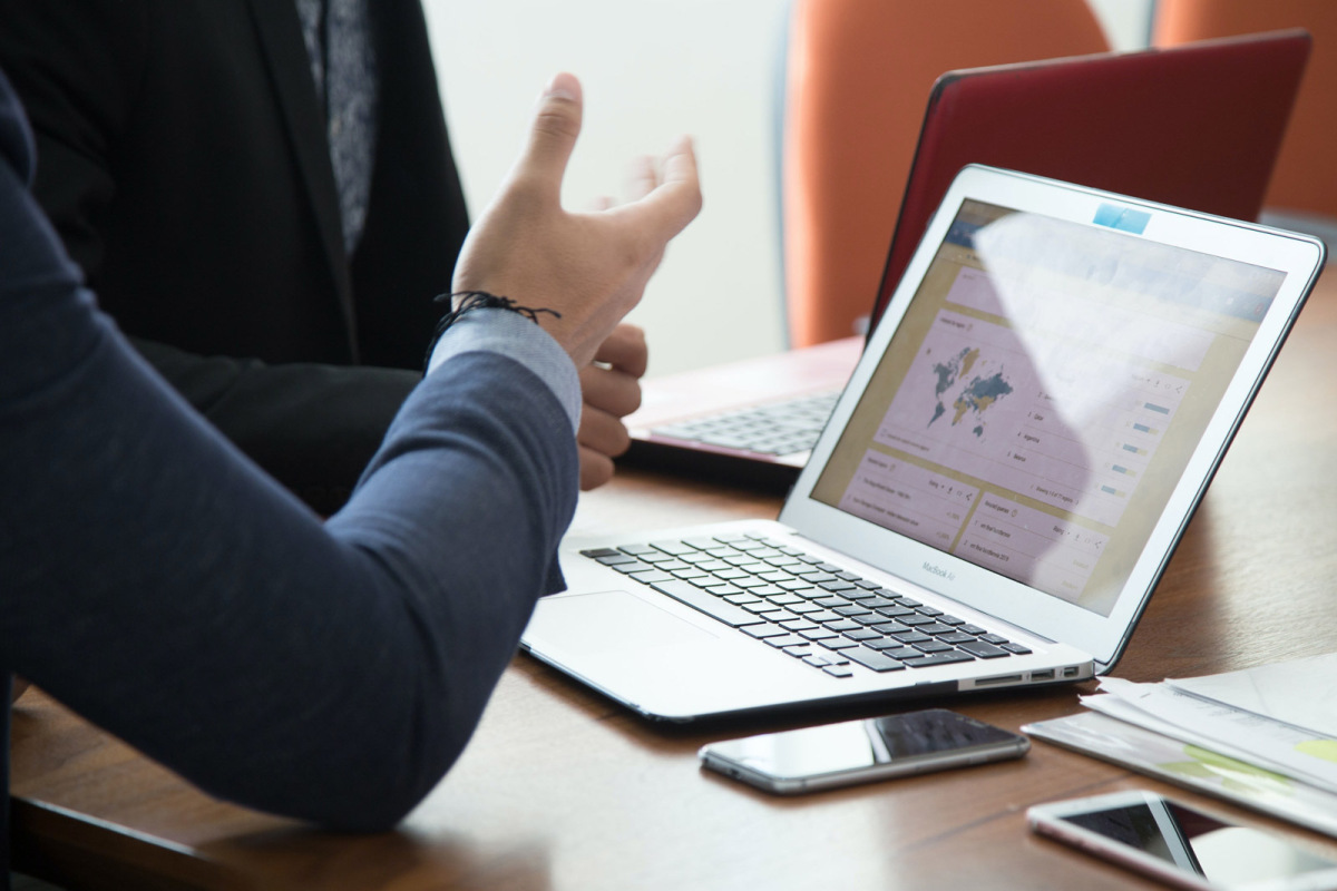 A women with a computer in front of her and speaking with a man beside her