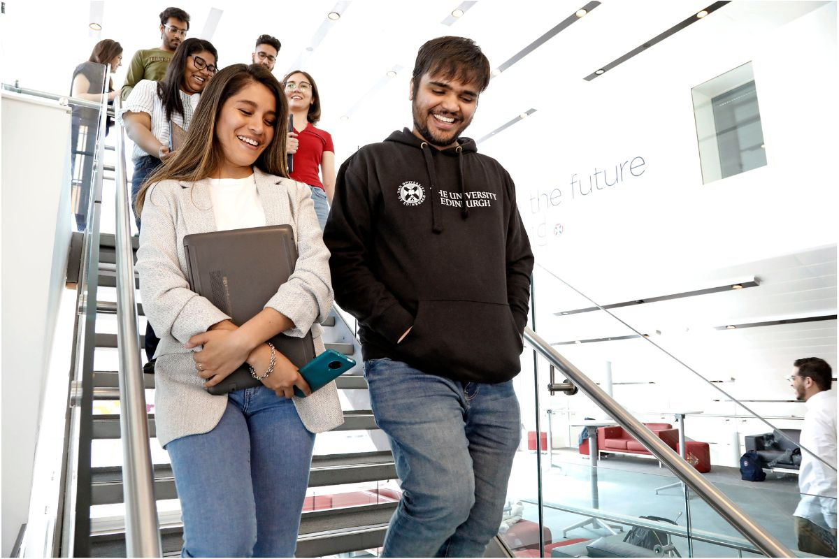 Pairs of students walking down stairs inside the University of Edinburgh Business School
