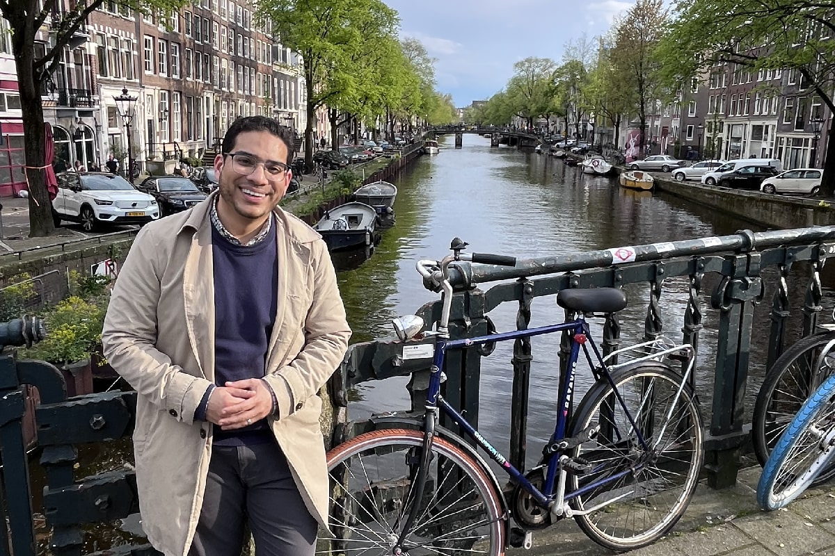 Elaf Basri standing in front of a canal and a bicycle in Amsterdam