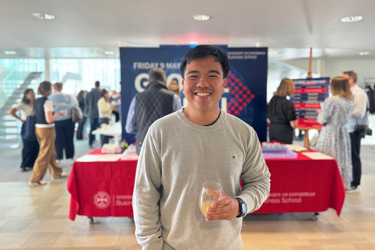 MSc Management Student, Nial, stands in front of the reception for Global Alumni Day 2025