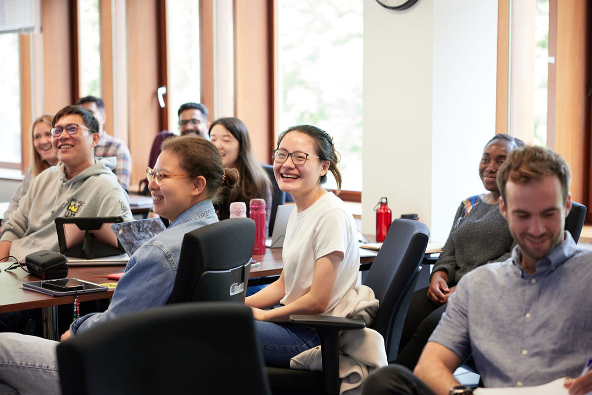 A classroom scene featuring several smiling MBA students sitting together, engaged in learning activities.
