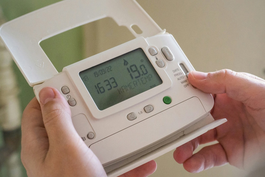 Hands holding an energy meter, details like date, time and temperature are indicated on the LCD display
